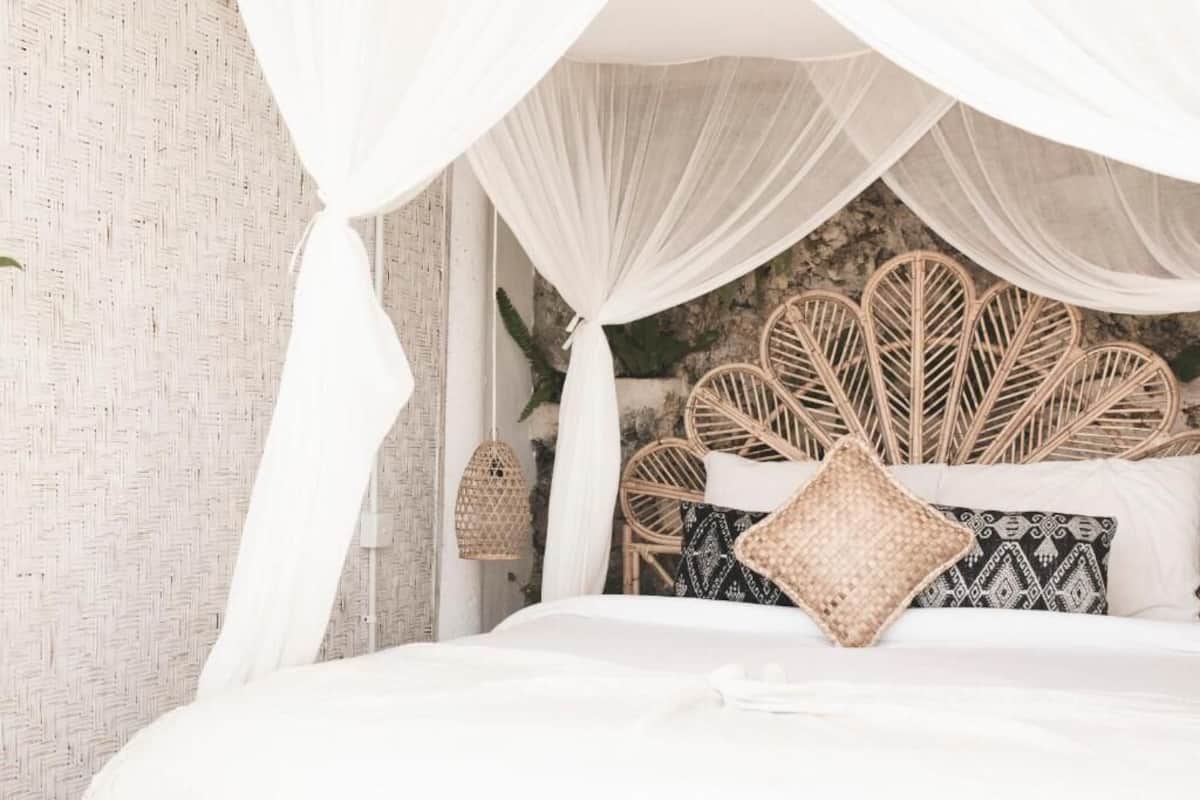 A bed with a canopy, a wicker headboard, and a patterned pillow.