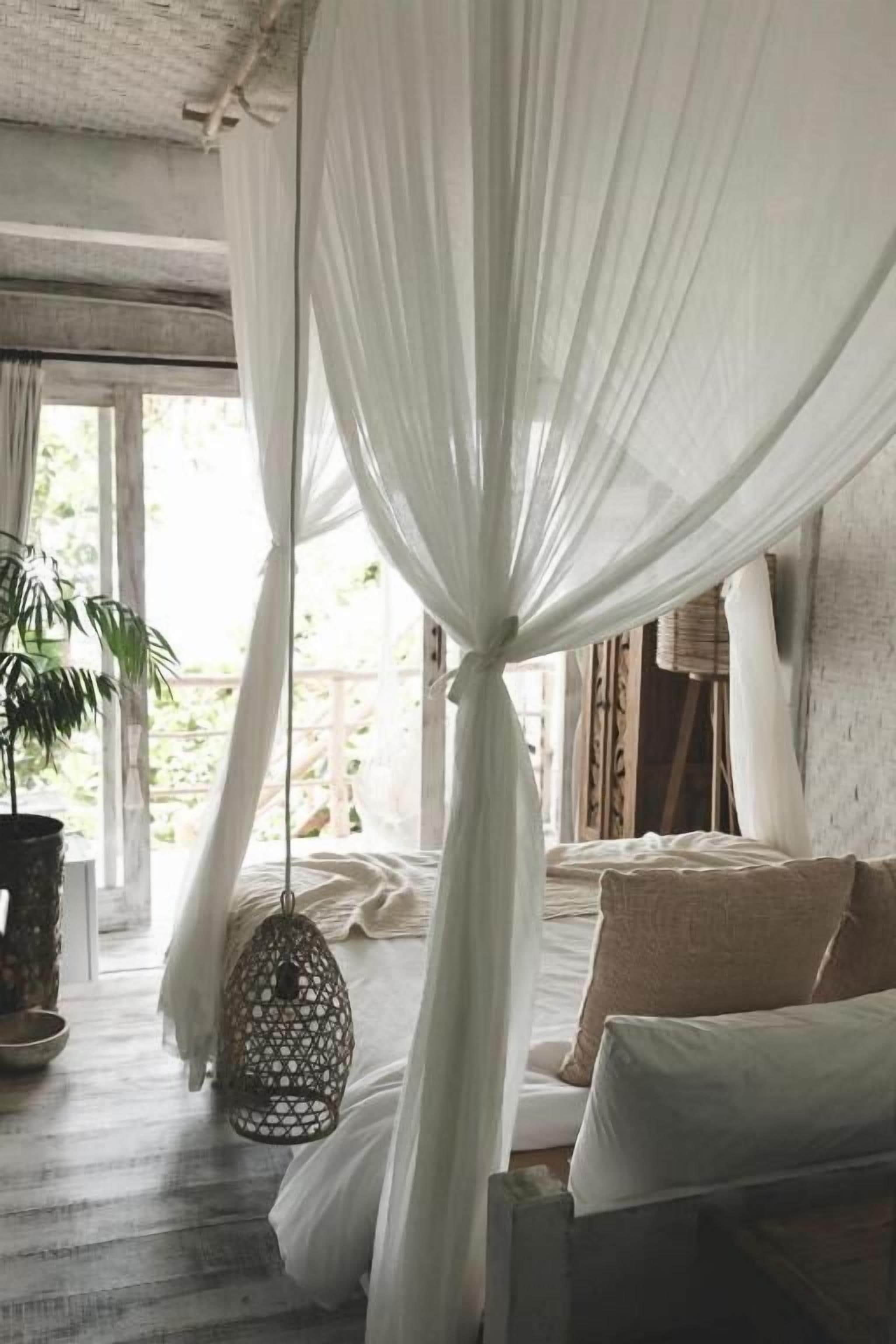 Un dormitorio con cama con dosel, un farol colgante y una planta en maceta.