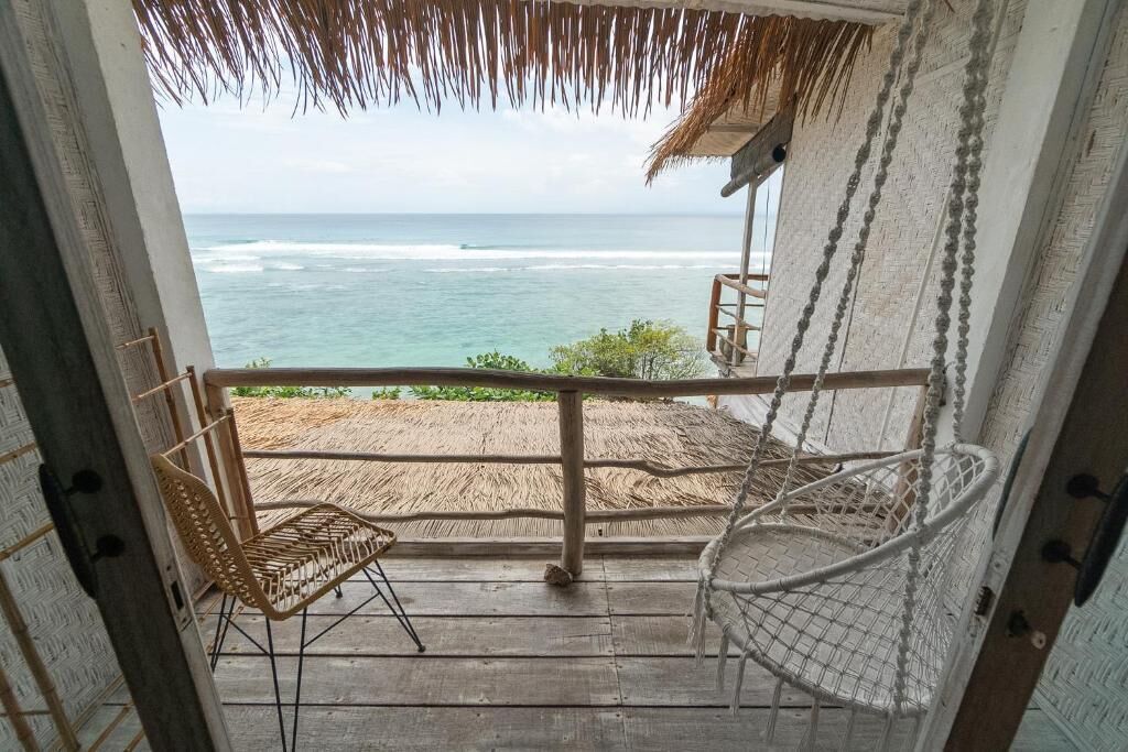 Un balcó amb vista a l'oceà, una cadira de vimetla i una cadira espanyola.