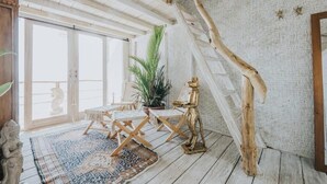 A rustic room with a wooden staircase, a dining area with a table and chairs, and a large potted plant. - Dreamsea Uluwatu (Pecatu)