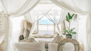 A room with a bed, white curtains, a view of the beach, and a potted plant. - Dreamsea Uluwatu (Pecatu)