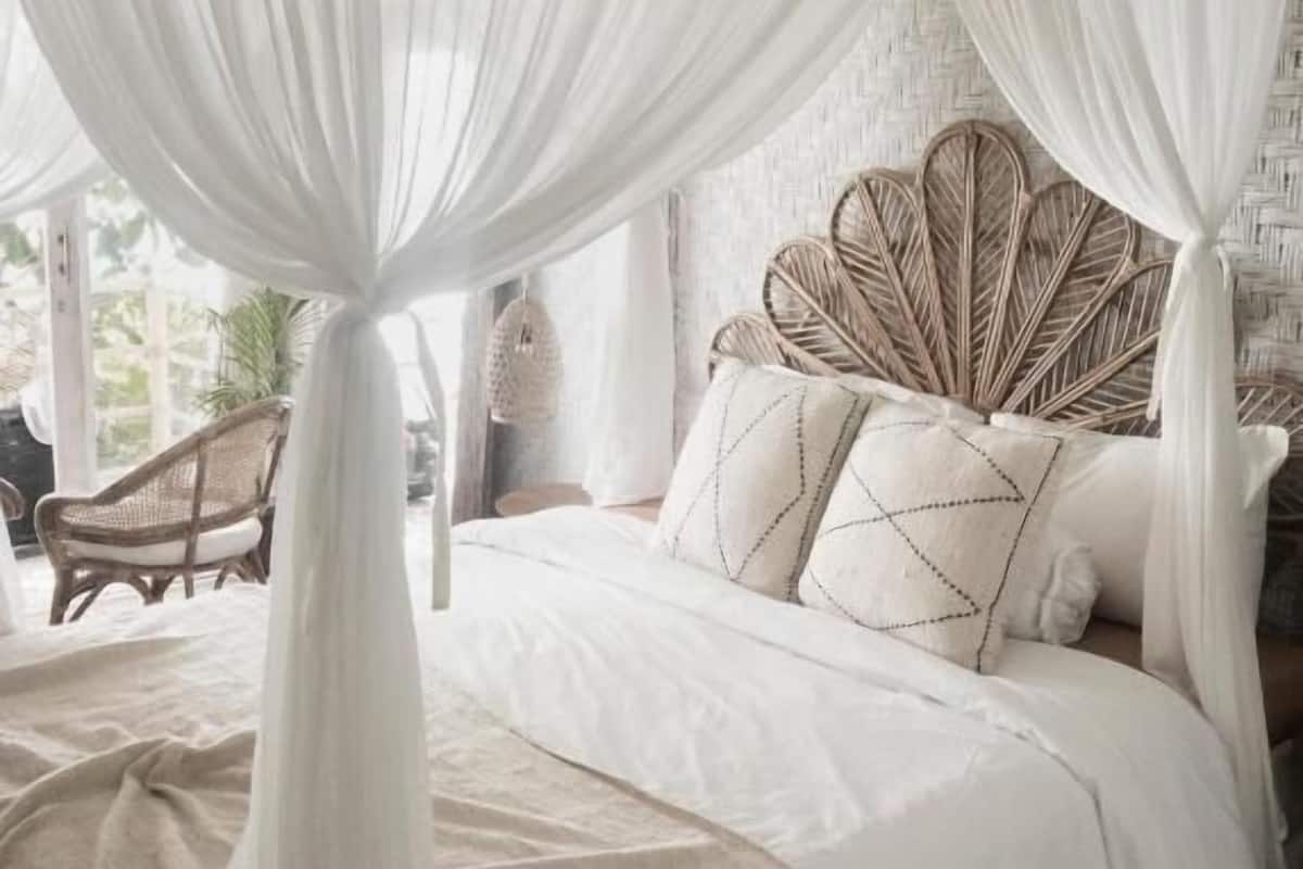 A bedroom with a canopy bed, a woven headboard, and a wicker chair.