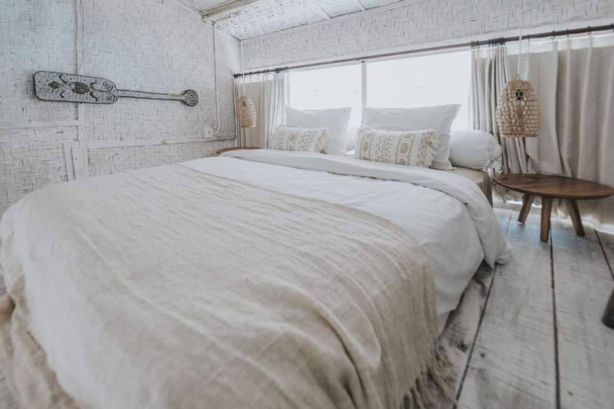 A bedroom with a large bed, a small round table, and a window with curtains.