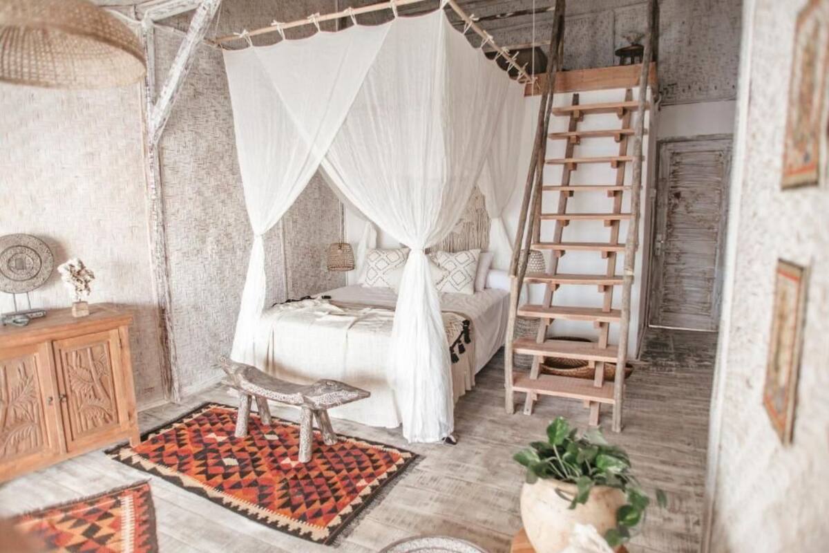 A bedroom with a four-poster bed, a ladder, and a small table.