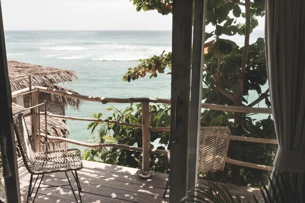 A wooden deck with wicker chairs overlooking the ocean.