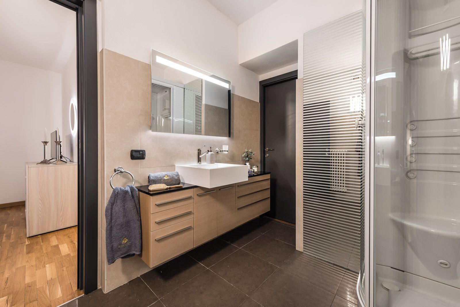 Un baño moderno con un espejo grande, un lavabo y una zona de ducha.