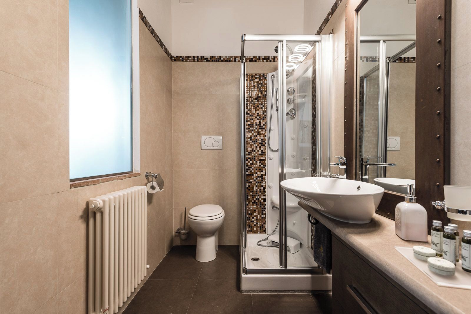 Un baño con ducha de vidrio, inodoro blanco, lavamanos grande y espejo.