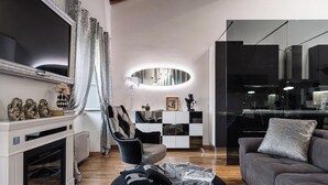 A modern living room with a fireplace, a large mirror, a sofa, and a dining area with a glass partition. - Giotto (Matraia)