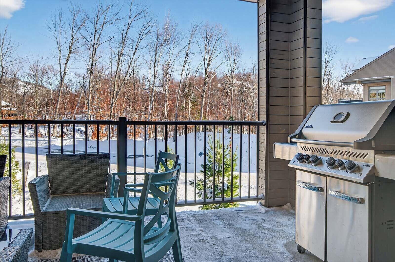A covered patio with outdoor furniture, a grill, and a view of a snowy landscape.