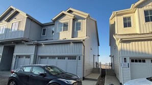 A two-story building with a garage on the ground floor and a driveway. - A home away from home. YEG retreat (Edmonton)