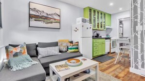 Uma sala de estar moderna com um sofá cinzento, uma mesa de centro branca e uma pintura de montanhas.