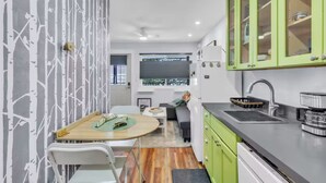 Cozinha compacta com área de refeições, incluindo uma mesa, cadeiras e vista pela janela.