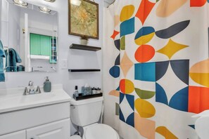 A modern bathroom with a white sink, a mirror, a green cabinet, and a shower curtain with a geometric pattern. - Alpine Edge, Top-Floor Ski Condo with Mountain Views adjacent to Ski Area (Steamboat Springs)