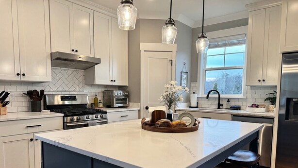 A modern kitchen with white cabinets, a large island, stainless steel appliances, pendant lighting, and a window with a view. - Scenic Sky Retreat | EV Charger & Skyline Views (Chattanooga)