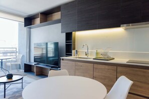 A modern kitchen with a built-in TV, a sink, and a dining area with a round table and chairs. - 2BR/1BA Apartment Perfect for Families with Pool! (Ñuñoa)