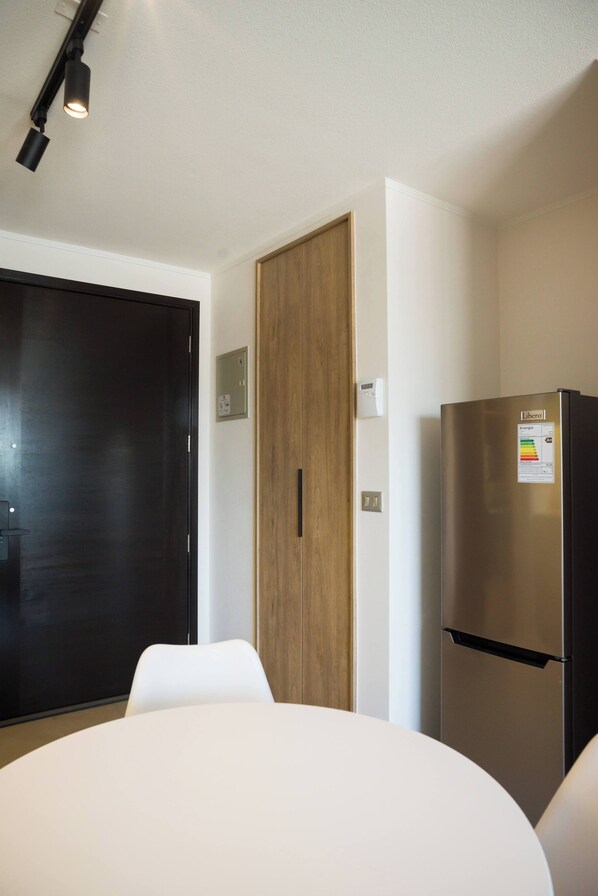 Eine moderne Küche mit einem Edelstahl-Kühlschrank, einer Holztür und einem weißen Tisch.