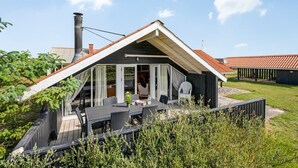 Una casa moderna con techo inclinado, un área de estar al aire libre techada y una chimenea.