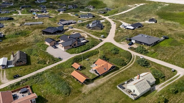 Vista aérea de una zona residencial costera con casas, carreteras y una playa.