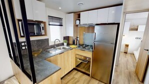 A compact kitchen with a microwave, stove, sink, and oven. - Family vacation near La Palmyre zoo (Les Mathes)