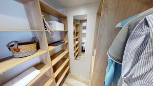 A narrow walk-in closet with wooden shelves and a mirrored closet door. - Family vacation near La Palmyre zoo (Les Mathes)