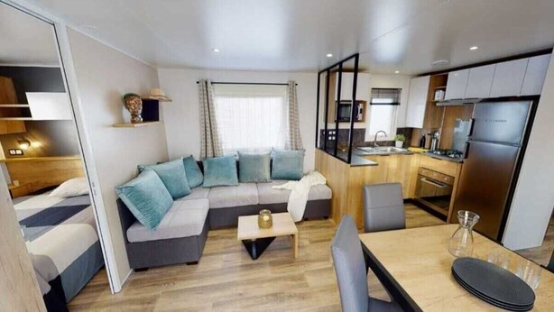 A compact living space with a sofa, a dining table, and a kitchenette. - Family vacation near La Palmyre zoo (Les Mathes)