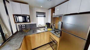 A compact kitchen with a built-in microwave, stainless steel appliances, and wooden cabinets. - Family vacation near La Palmyre zoo (Les Mathes)