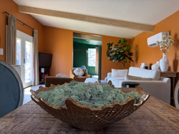 A living room with a wooden table, a white sofa, and a green plant.