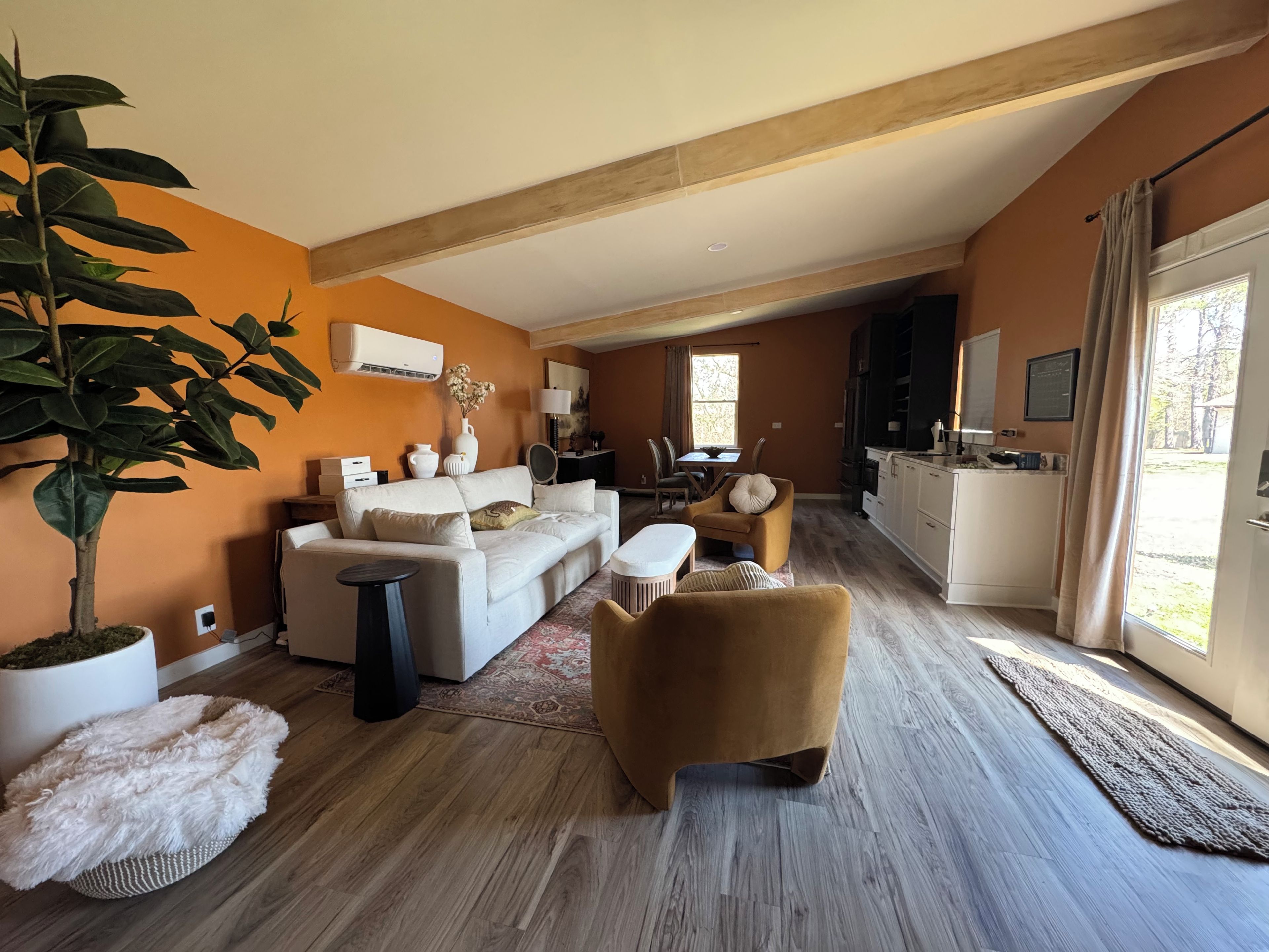 Un grand espace de vie comprenant un canapé, des fauteuils, une table à manger et une cuisine à l’arrière-plan.