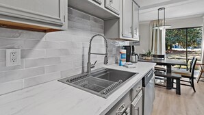 Een moderne keuken met witte kasten, een roestvrijstalen spoelbak en een ingebouwde oven.