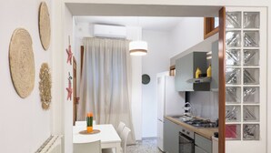 A modern kitchen with a central island, white cabinetry, and a dining area with a table and chairs. - Amazing 2-bedroom apartment in adorable Monopoli with AC (Monopoli)