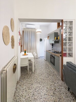 A modern kitchen with a central island, white cabinetry, and a dining area with a table and chairs. - Amazing 2-bedroom apartment in adorable Monopoli with AC (Monopoli)