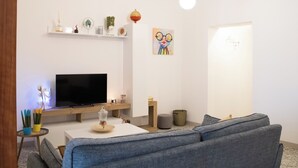 A modern living room with a flat-screen TV, grey sofa, and decorative items on shelves. - Amazing 2-bedroom apartment in adorable Monopoli with AC (Monopoli)