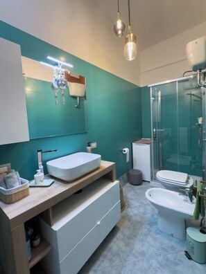 A modern bathroom with a large mirror, two sinks, a shower, and a toilet. - Amazing 2-bedroom apartment in adorable Monopoli with AC (Monopoli)