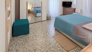 A bedroom with a bed, a TV, a wardrobe, and a mirror. - Amazing 2-bedroom apartment in adorable Monopoli with AC (Monopoli)