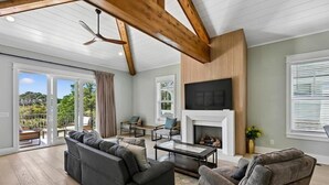 A spacious living room with a fireplace, a large sofa, a coffee table, and a television mounted on the wall. - Stunning Vacation Home Just Steps to the Beach! (Hilton Head Island)