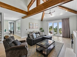 A spacious living room with a sectional sofa, a glass coffee table, and a ceiling fan. - Stunning Vacation Home Steps to the Beach! (Hilton Head Island)