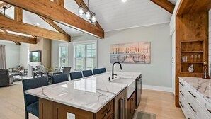 A spacious kitchen with a large island, wooden beams, and a view of the beach. - Stunning Vacation Home Just Steps to the Beach! (Hilton Head Island)