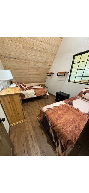 A bedroom with two beds, wooden ceiling, and a window. - Beautiful 3-bedroom barn in charming Kanarraville (Kanarraville)