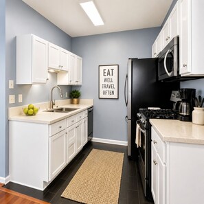 A modern kitchen with white cabinets, a stainless steel sink, a microwave, and a stove. - Signature Reserve Atlanta Luxury 3BR Townhome Near ATL Airport Sleeps 6 (Atlanta)