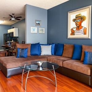 A modern living room with a sectional sofa, a glass coffee table, and a dining area with a table and chairs. - Signature Reserve Atlanta Luxury 3BR Townhome Near ATL Airport Sleeps 6 (Atlanta)