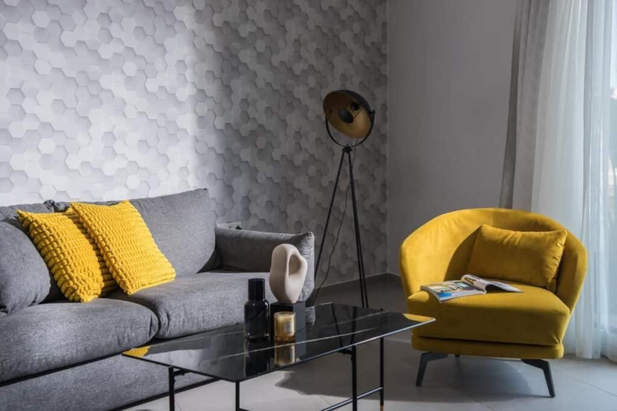 Ein modernes Wohnzimmer mit einem grauen Sofa, gelben Kissen, einem schwarzen Couchtisch und einem gelben Sessel.