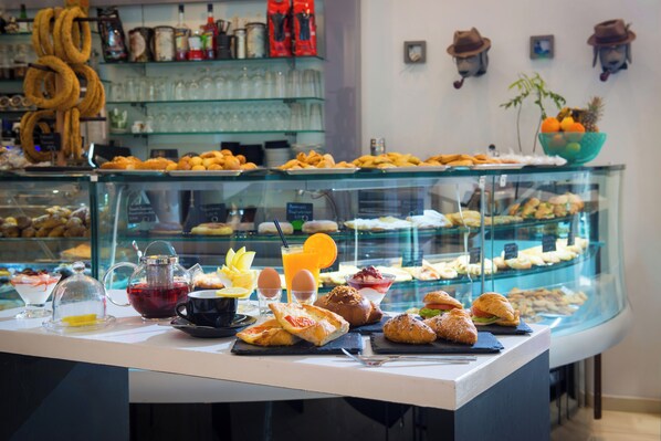 A breakfast buffet with various pastries, a coffee station, and a fruit bowl.