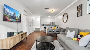 A modern living room with a grey sofa, a round black coffee table, and a flat-screen TV mounted on the wall. - Lucayan Harbour Kissimmee Home with Pool, Sleeps 12, Near Disney World (Kissimmee)