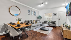 A modern living room with a dining area, grey sofas, a round mirror, and a large painting on the wall. - Lucayan Harbour Kissimmee Home with Pool, Sleeps 12, Near Disney World (Kissimmee)