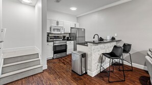 A modern kitchen with white cabinetry, stainless steel appliances, and a small island with bar stools. - Lucayan Harbour Kissimmee Home with Pool, Sleeps 12, Near Disney World (Kissimmee)