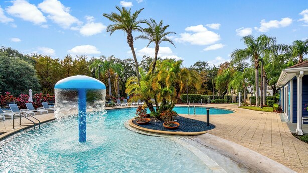 A pool area with a water feature, palm trees, and lounge chairs. - Lucayan Harbour Kissimmee Home with Pool, Sleeps 12, Near Disney World (Kissimmee)