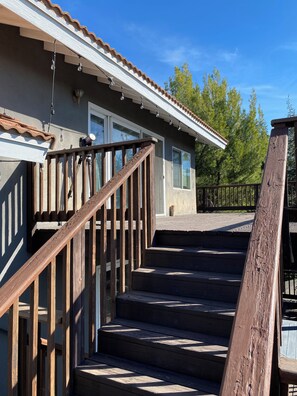 Un escalier en bois mène à un bâtiment à l’extérieur blanc et au toit brun.