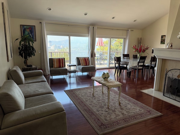 A spacious living room with a sofa, armchairs, a dining table, and a fireplace.