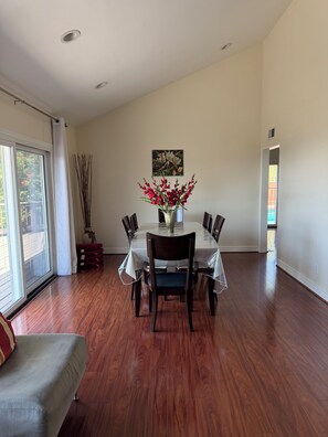 A dining area with a table, chairs, a vase with flowers, a painting on the wall, and a view through a window. - Cozy 5-bedroom home with Stunning Views in Prestigious Glendale hills (Glendale)