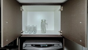 A minibar with a bottle and four glasses. - Loft Moderno Centro Itajaí (Itajaí)